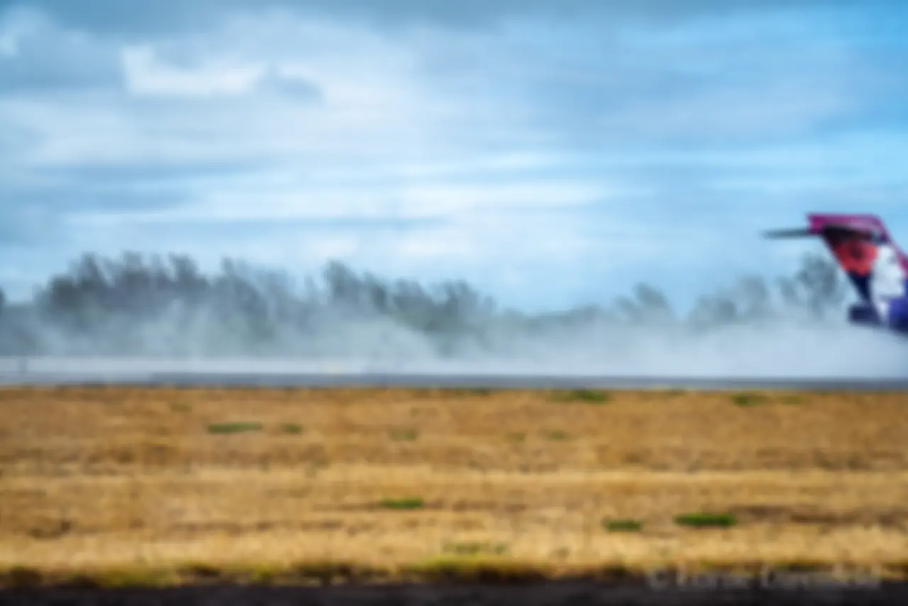 A Hawaiian airlines B717 lands at Kahului airport on a wet runway, kicking up the mist . . .
