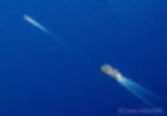 A tug and barge cut a swath through the blue Pacific Ocean . . .